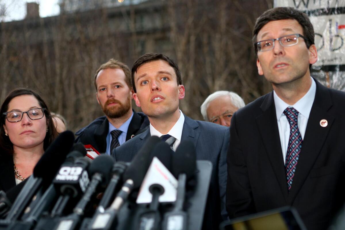 Washington state's solicitor general, Noah G. Purcell, center, who will argue the state's case to the appeals court, and state Atty. Gen. Bob Ferguson, right, at a news conference Friday in Seattle.