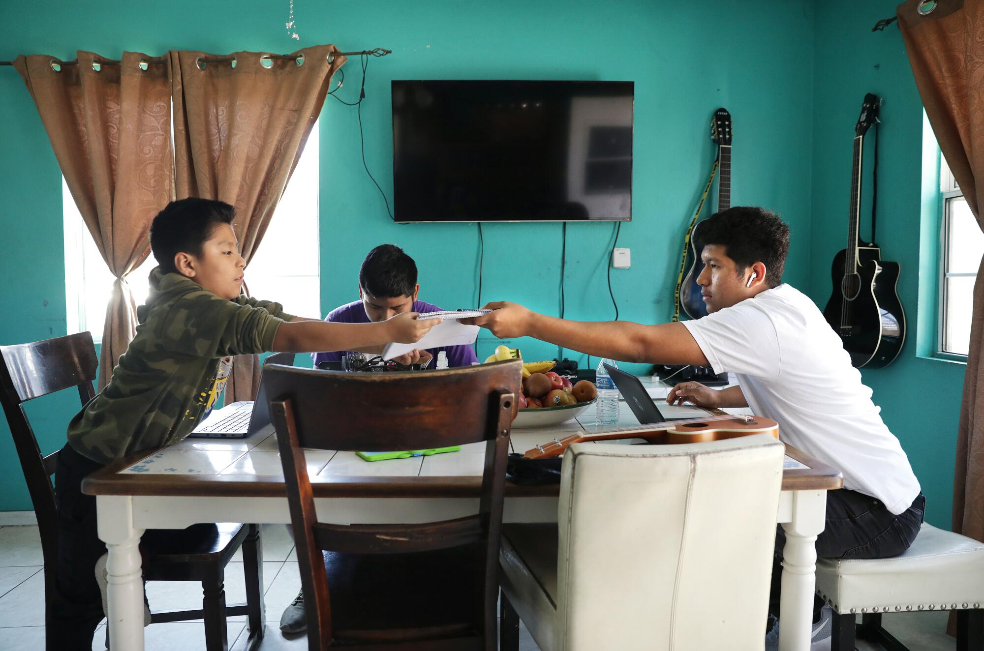 Julio Flores, right, with brothers Angel, left, and David, do schoolwork at home