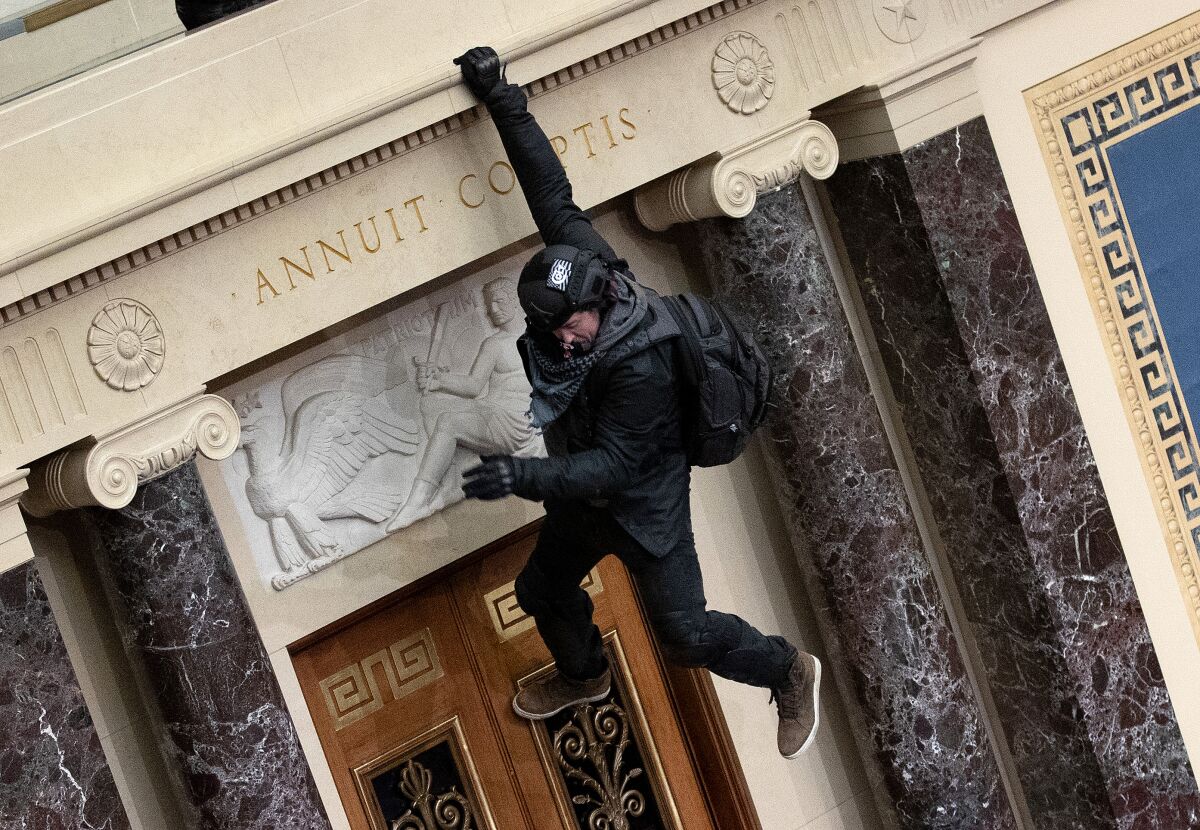 A rioter supporting President Trump jumps from the public gallery to the floor of the Senate Chamber.