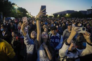 FILE - People take smartphone photos of the crowd on a street near Tiananmen Square as visitors gather to watch a flag-raising ceremony on the National Day in Beijing, Sunday, Oct. 1, 2023. The world’s population is expected to grow by more than 2 billion people in the next decades and peak in the 2080s at around 10.3 billion, a new report by the United Nations said Thursday July 11, 2024. (AP Photo/Andy Wong, File)