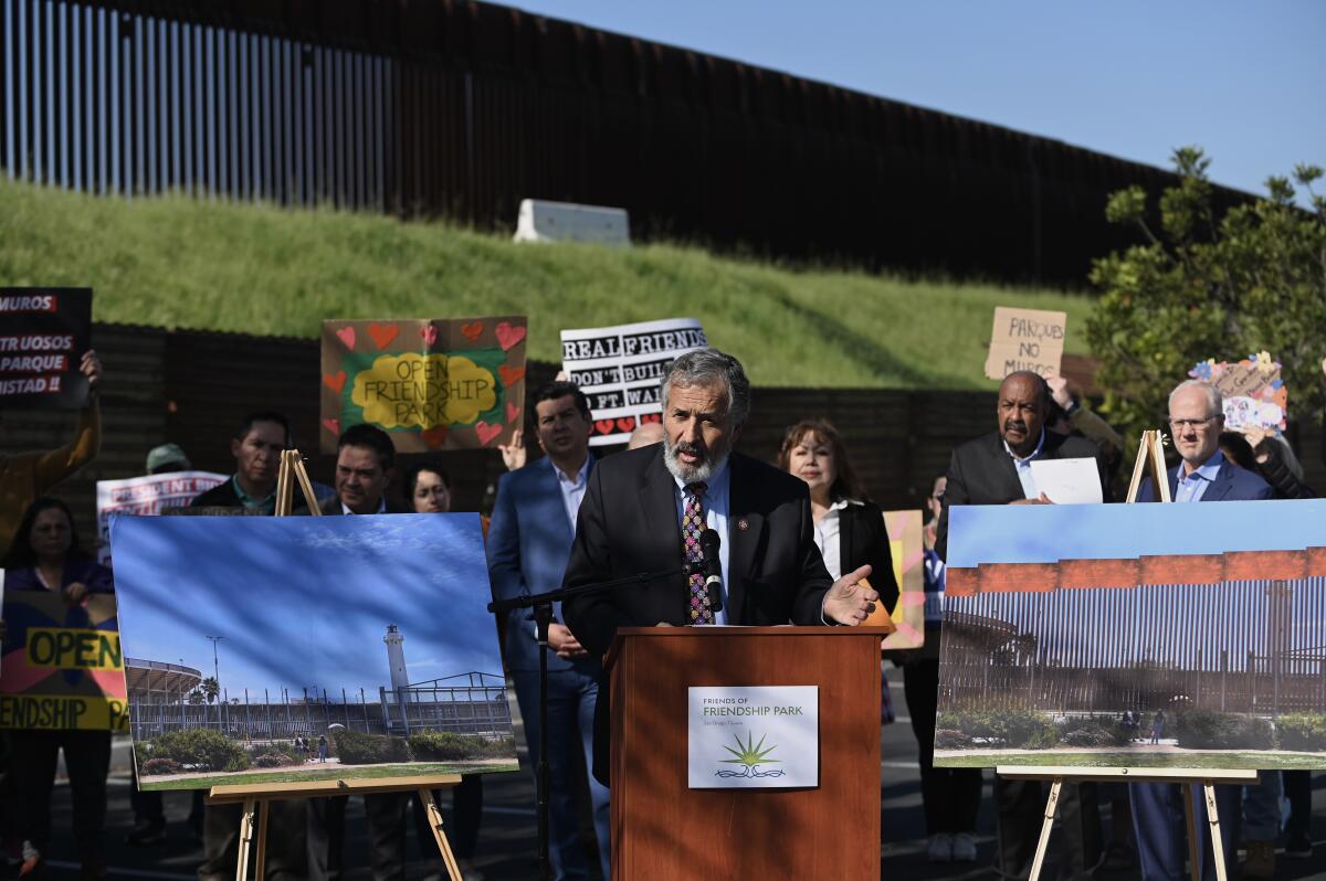 Rep. Juan Vargas at a news conference next to a border fence.