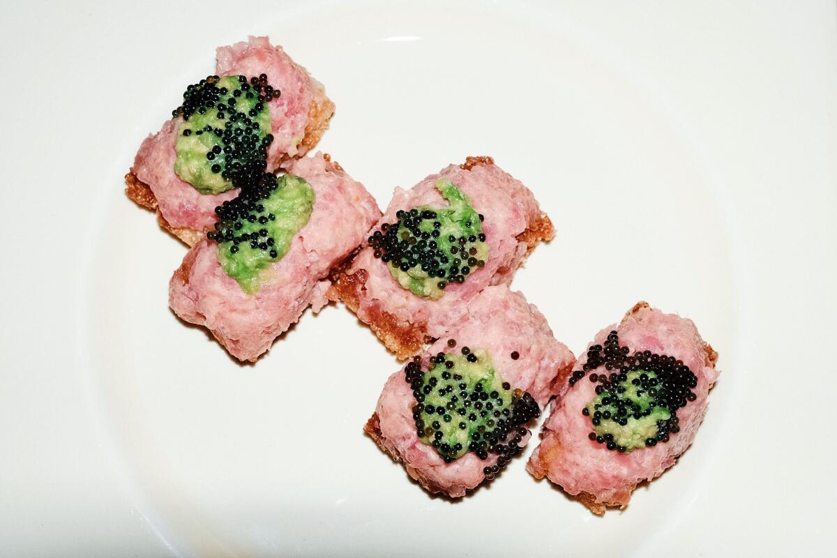 An overhead photo of five pieces of staggered caviar-topped tuna crispy rice with avocado.
