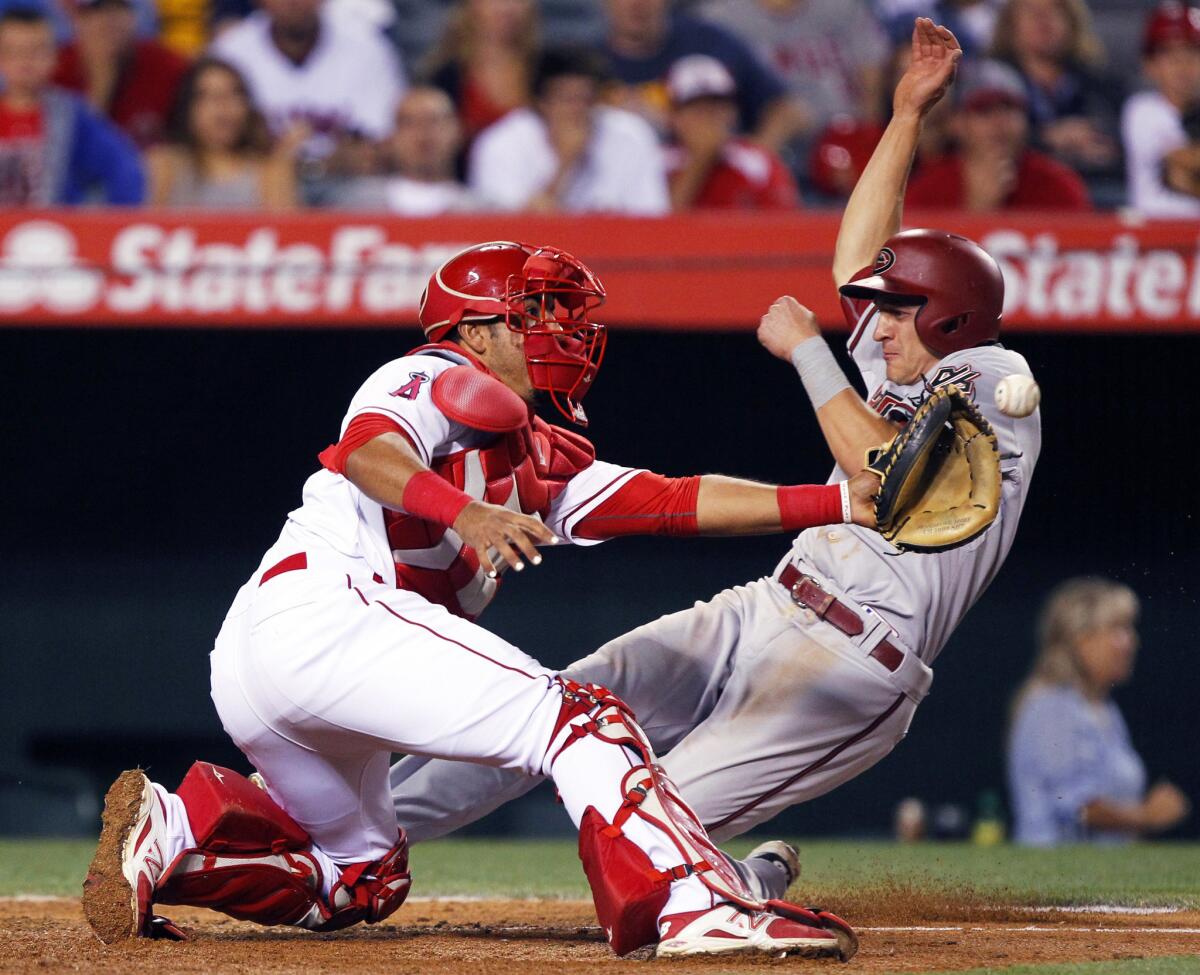 Angels catcher Carlos Perez takes the throw as Arizona's Nick Ahmed scores on a sacrifice fly in the ninth inning Monday night in Anaheim.