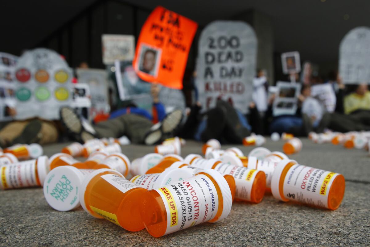 Containers depicting OxyContin prescription pill bottles on the ground.  