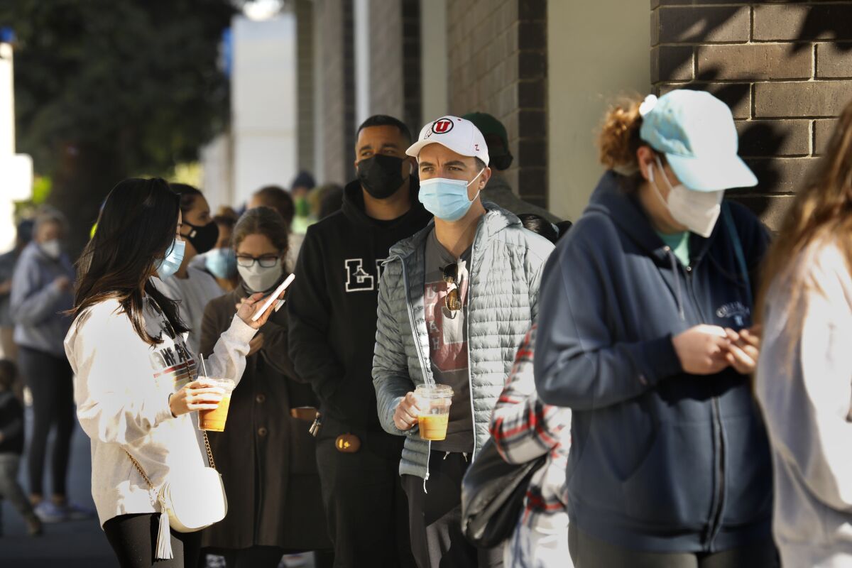 People in face masks wait in line outside a building