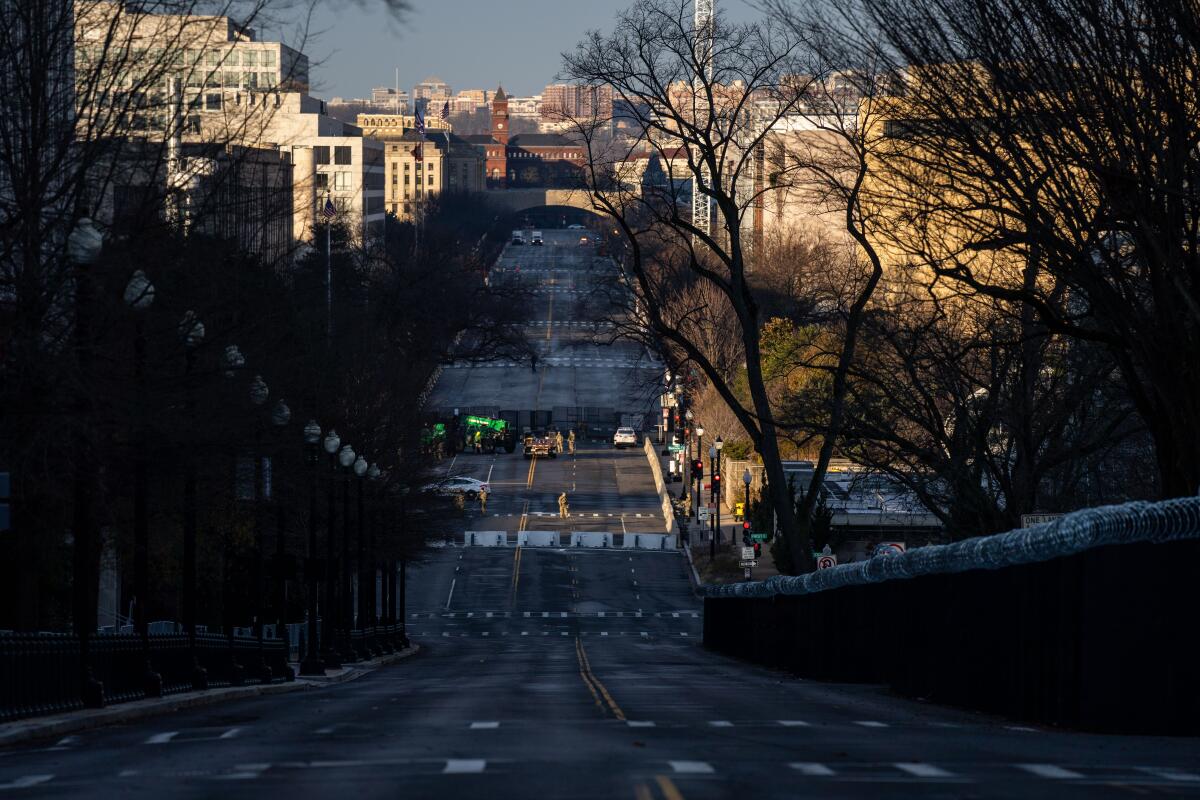 Downhill view of an empty street in Washington, D.C., with barricades and troops seen in the distance