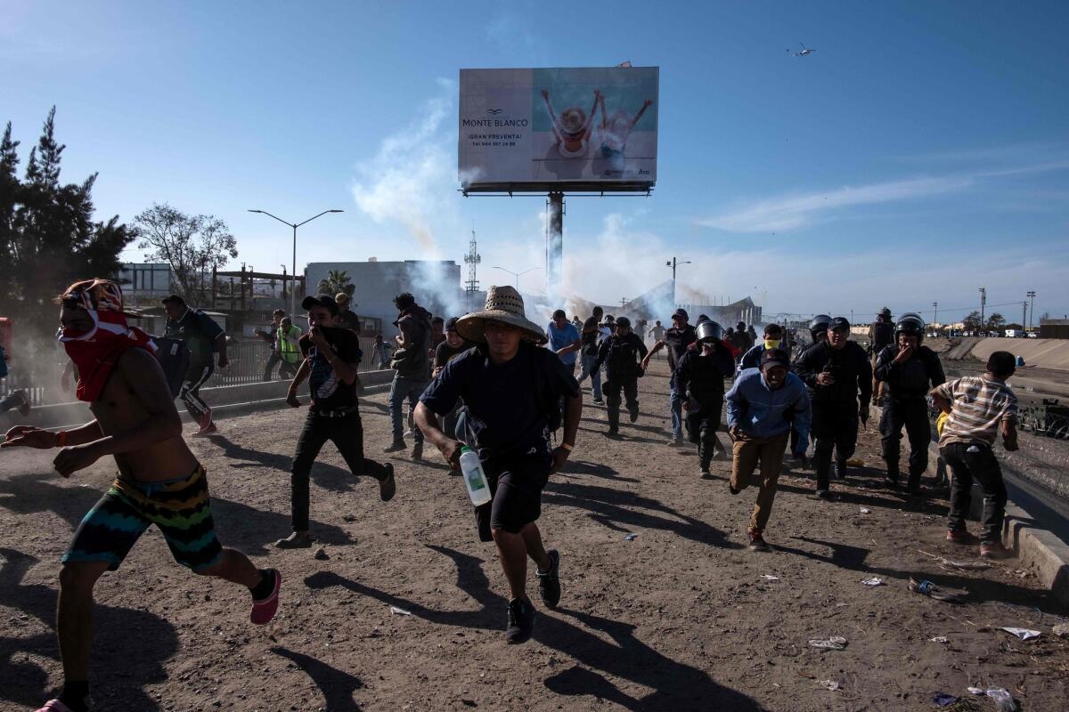 Central American migrants run along the Tijuana River near the Chaparral border crossing in Tijuana near the U.S.-Mexico border, after the U.S. Border Patrol used tear gas on Nov. 25, 2018.