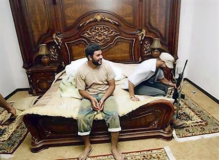 Anti-Gaddafi forces sit on a bed at Muammar Gaddafi's farm house near the town of Abu Grein