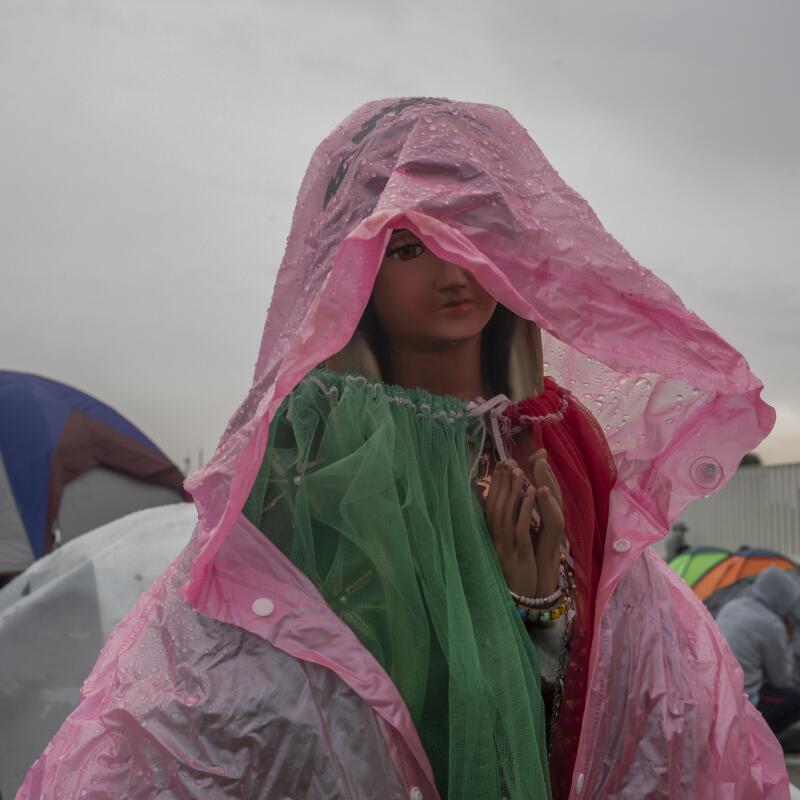 A figure of the Virgin of Guadalupe covered with a plastic bag to protect the figure from the rain