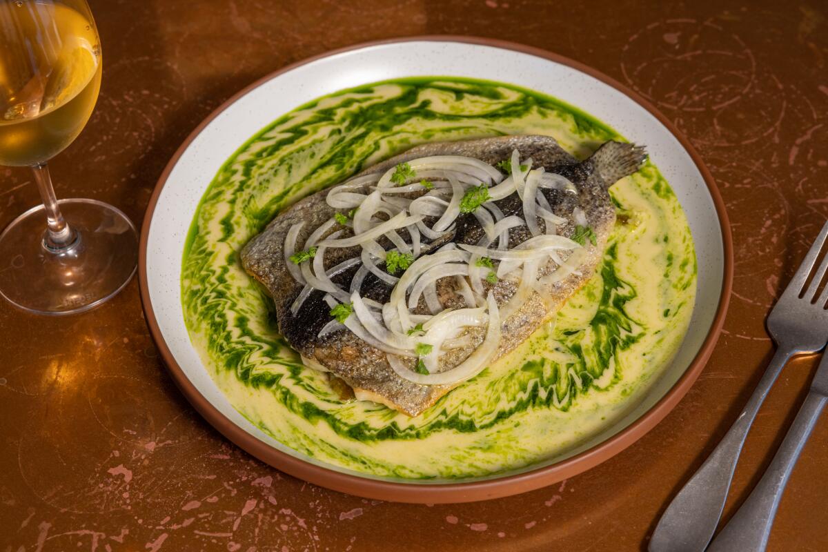 A trout dish in a yellow-green sauce topped with onions from Bar Chelou