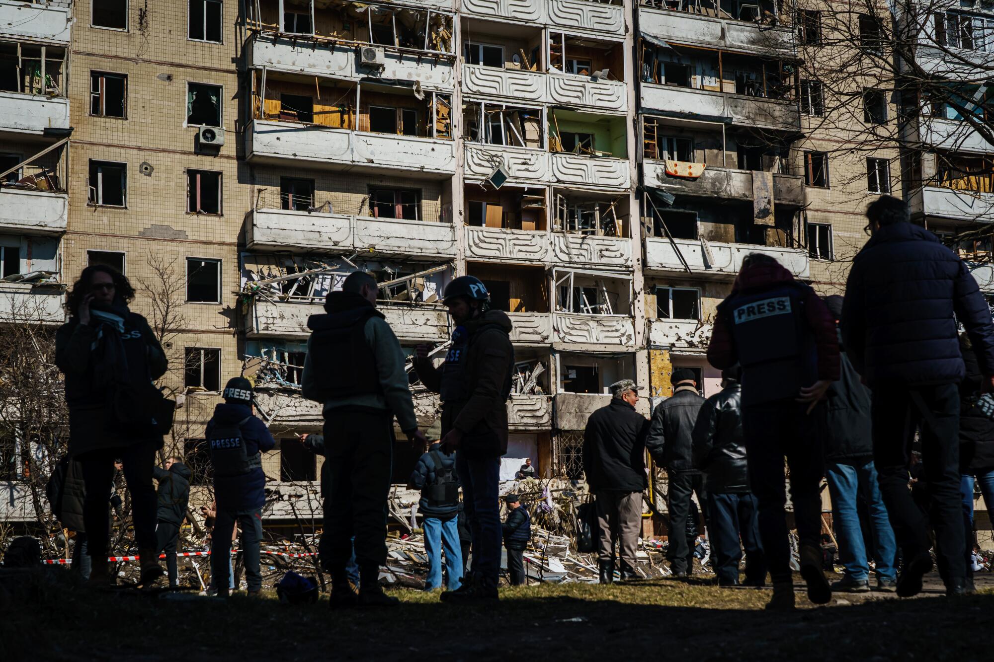 Reporters and local residents stand outside a residential building that was damaged by a Russian missile strike in Kyiv