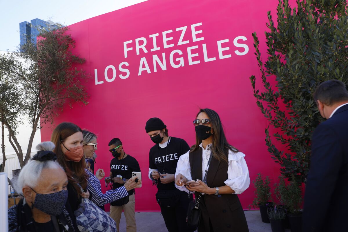 Masked attendees in front of wall that says Frieze Los Angeles