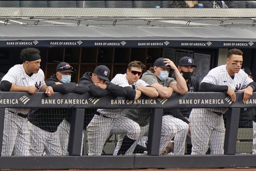 New York Yankees players lean on the dugout railing during the seventh inning of a loss to the Tampa Bay Rays in a baseball game, Sunday, April 18, 2021, at Yankee Stadium in New York. From left to right, are: designated hitter Giancarlo Stanton, outfielder Brett Gardner, who did not play Sunday, retiring outfielder Jay Bruce, DJ LeMahieu, injured first baseman Luke Voit, a coach and Aaron Judge. (AP Photo/Kathy Willens)