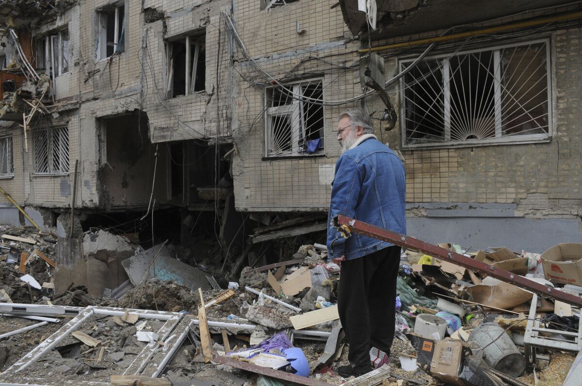 A man stands next to an apartment building damaged by shelling in Kharkiv, Ukraine, Sunday, April 10, 2022. (AP Photo/Andrew Marienko)