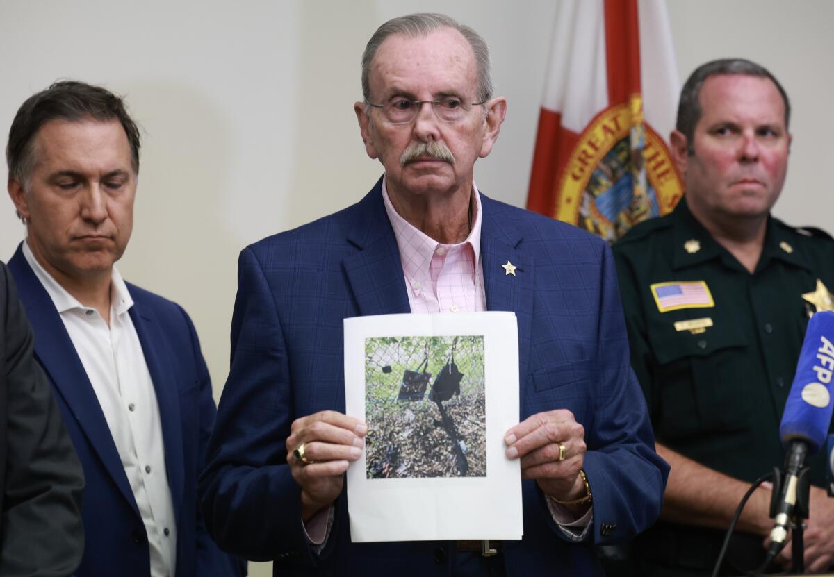 Palm Beach County Sheriff Ric Bradshaw holds a photograph of the rifle found near where a suspect was discovered.