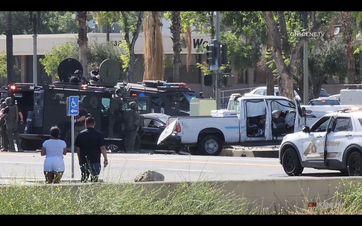 A pickup truck sits on a curb surrounded by police and armored vehicles.