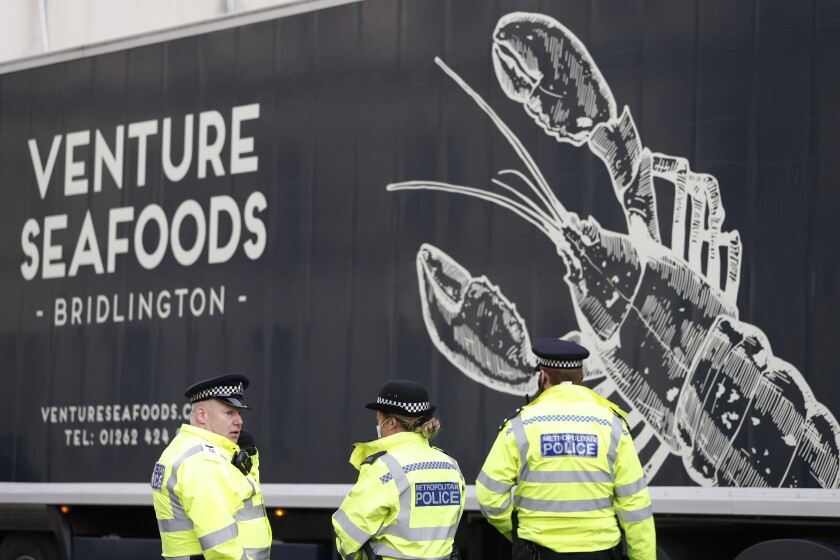 Police speak to a shellfish export truck driver as he is stopped for an unnecessary journey in London, Monday, Jan. 18, 2021, during a demonstration by British Shellfish exporters to protest Brexit-related red tape they claim is suffocating their business. The drivers were later stopped by police and issued with fines for an 'unnecessary journey' due to the national lockdown to curb the spread of the coronavirus. (AP Photo/Alastair Grant)