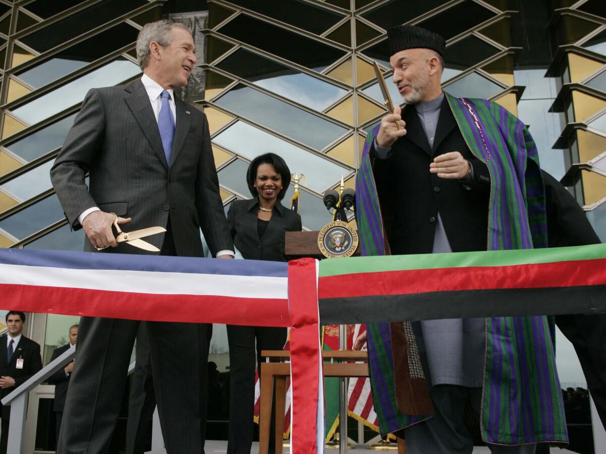 FILE - In this March 1, 2006 file photo, U.S. President George W. Bush, left and Afghan President Hamid Karzai get ready to cut a ribbon to officially open the U.S. Embassy in Kabul, Afghanistan. In an interview with German international broadcaster Deutsche Welle released Wednesday, July 14, 2021, Bush criticized the Western withdrawal from Afghanistan saying he fears that Afghan women and girls will “suffer unspeakable harm.” (AP Photo/Charles Dharapak, File)