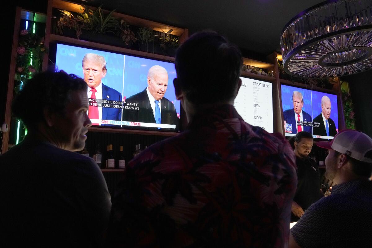 TV displays Trump and Biden debate at bar.