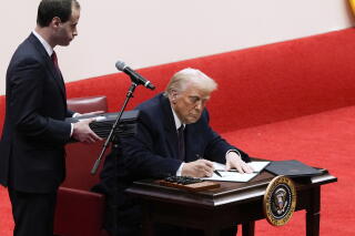 President Trump signs an executive order at an indoor presidential inauguration parade event in Washington on Jan. 20.