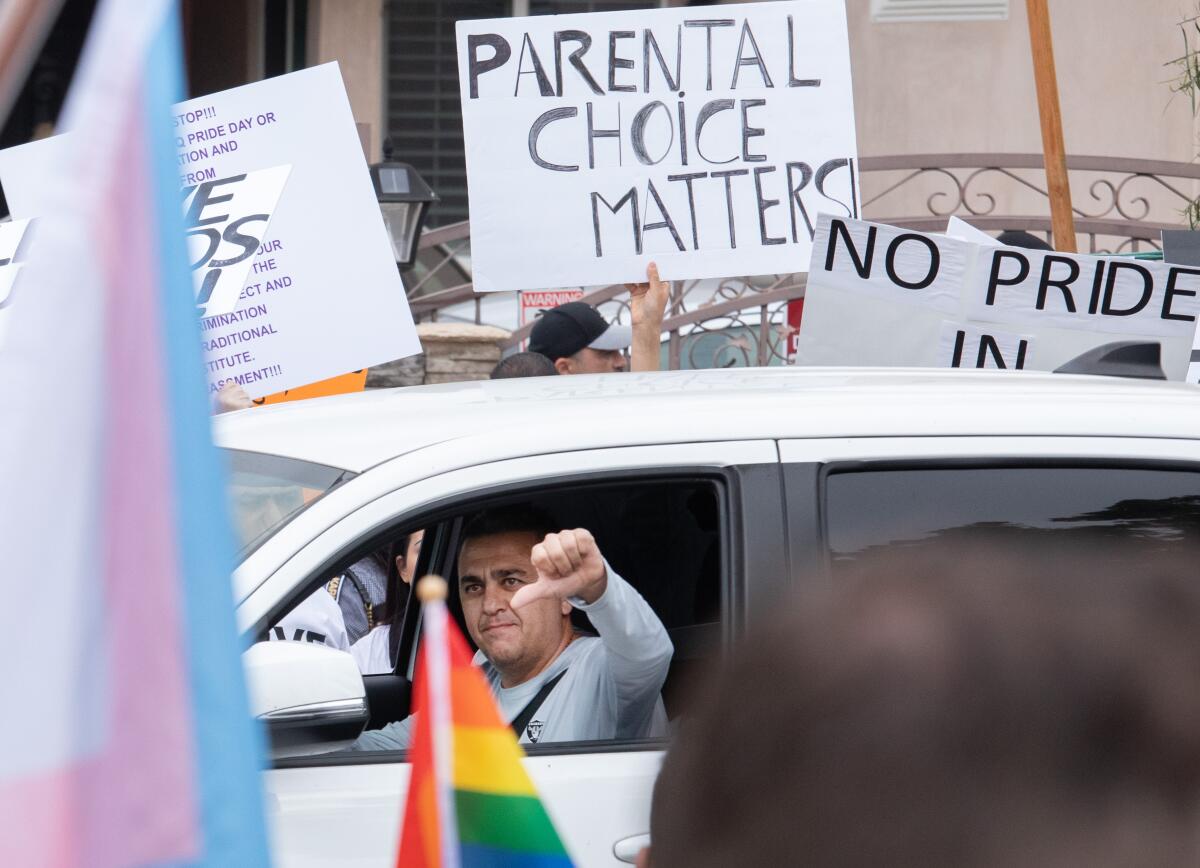 A   motorist gives a thumbs-down as he passes counterprotesters in front of Saticoy 