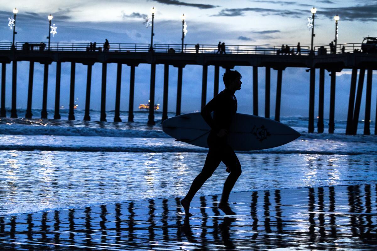 A surfer is silhouetted as he leaves the water in Huntington Beach.