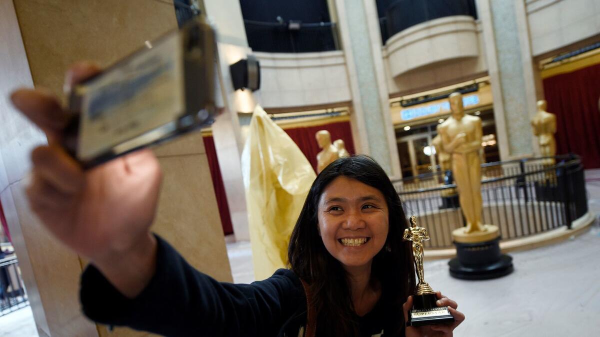 Susanne Wong, visiting from Brisbane, Australia, takes a selfie with Oscar statues in the Dolby Theater in Los Angeles. California could lose $1.7 billion from declines in tourism over the next two years, a UCLA report says.