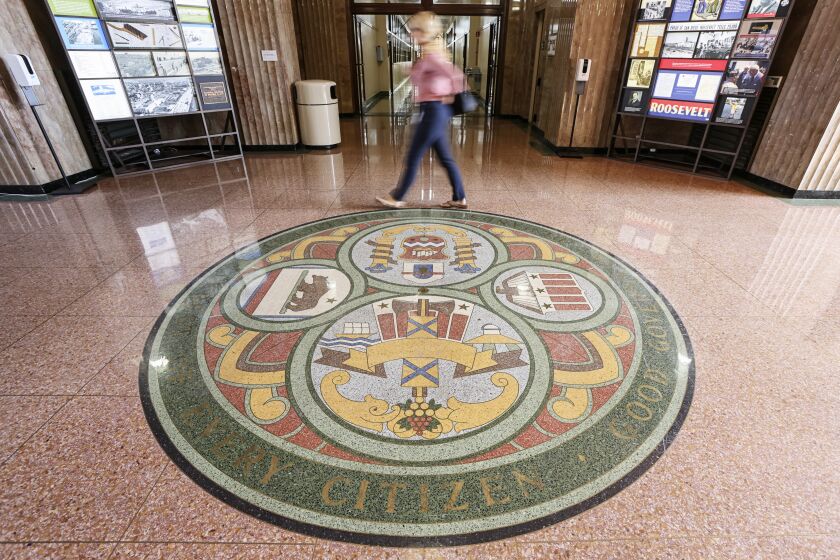 SAN DIEGO, CA - JULY 30: People walk past the county seal by the entrance at the San Diego County Administration Building on Friday, July 30, 2021 in San Diego, CA. San Diego County will require workers to get vaccines or tested. (Eduardo Contreras / The San Diego Union-Tribune)