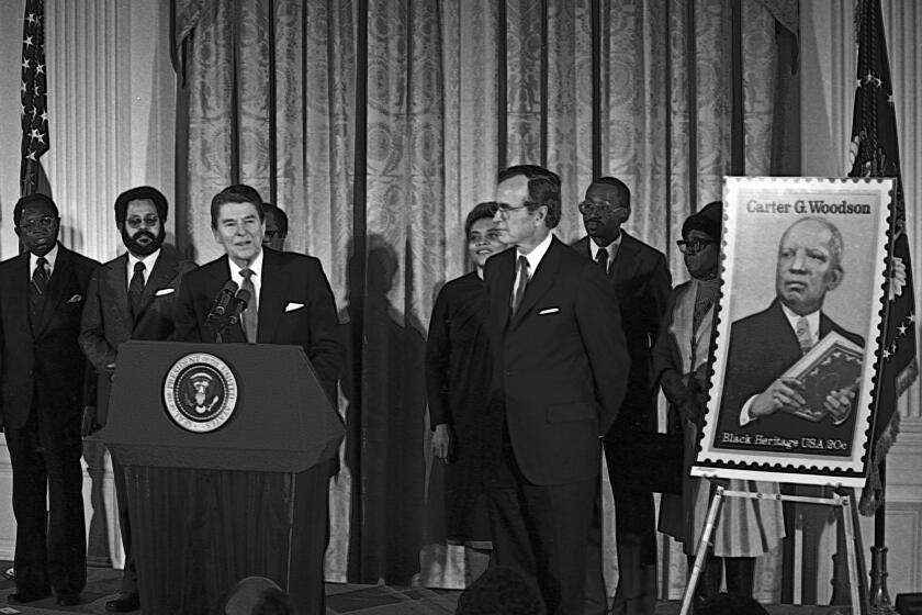 President Ronald Reagan unveils postage stamp of Carter Woodson (father of black history) at a White House Ceremony marking the observance of National Afro-American (Black) History Month, Washington DC, February 2, 1984. (Photo by Mark Reinstein/Corbis via Getty Images)