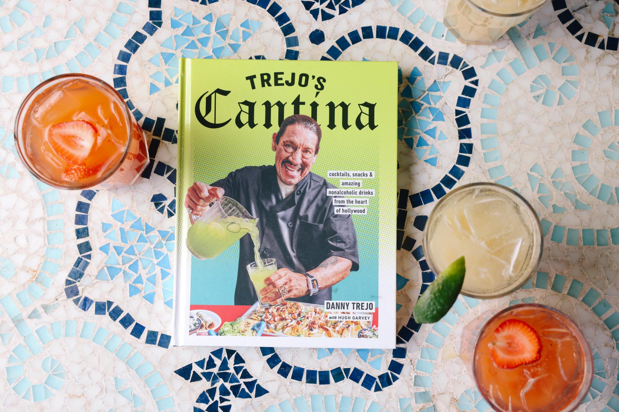 The "Trejo's Cantina" cookbook on a table surrounded by nonalcoholic beverages in glasses