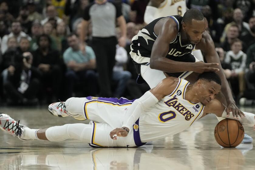 Milwaukee Bucks' Khris Middleton and Los Angeles Lakers' Russell Westbrook go after a loose ball during the second half of an NBA basketball game Friday, Dec. 2, 2022, in Milwaukee. (AP Photo/Morry Gash)