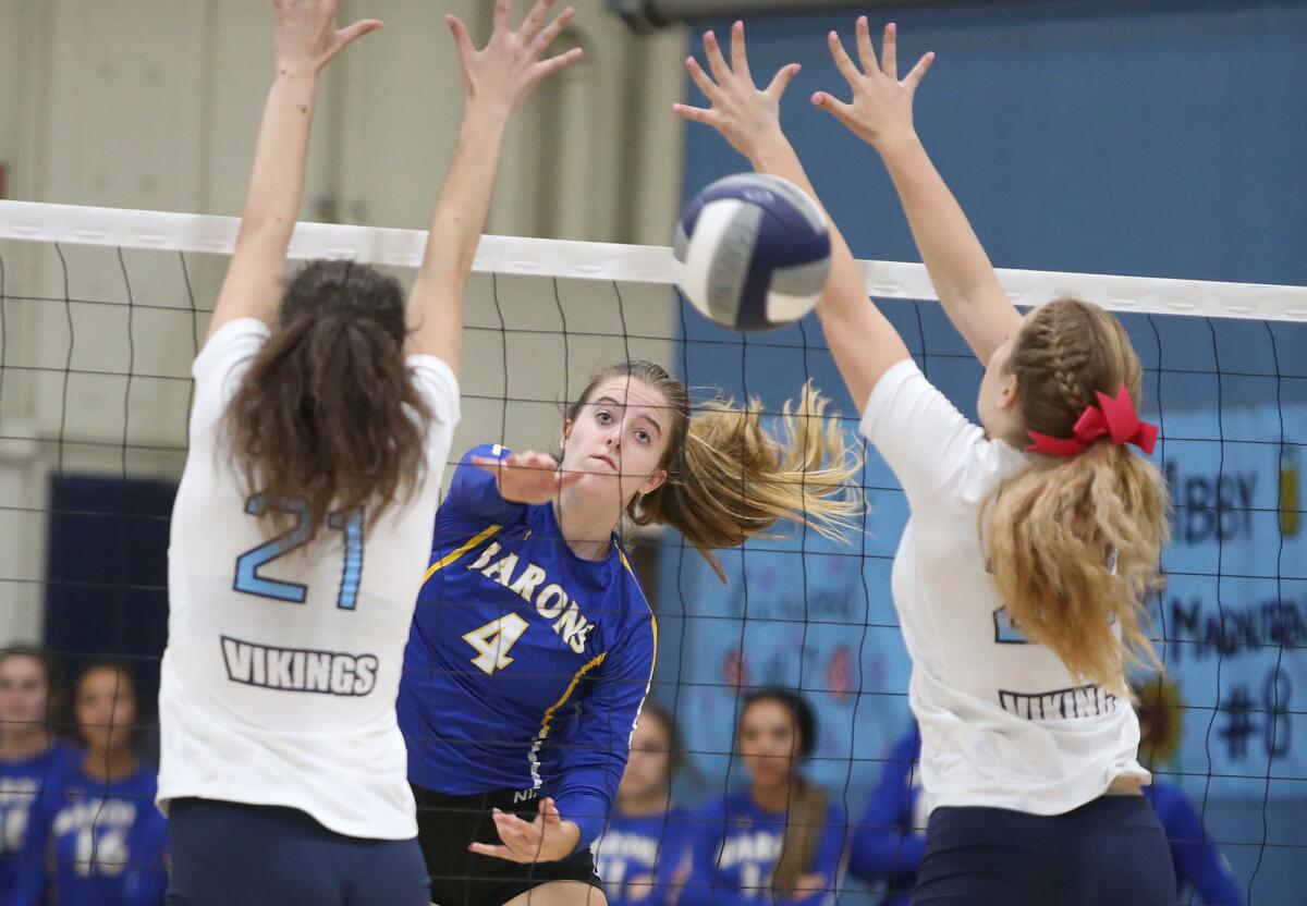 Fountain Valley's Phoebe Minch, center, puts the ball past Marina blockers Jane Paden, left, and Paige Phillips in a Wave League match in Huntington Beach on Tuesday.