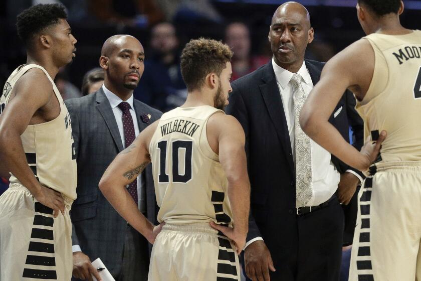 This photo from Nov. 28, 2017, shows Wake Forest assistant coach Jamill Jones, second from left, with the team and head coach Danny Manning, second from right, during the second half of an NCAA college basketball game in Winston-Salem, N.C. Police say Jones threw a punch that killed a New York City tourist who knocked on his car window thinking it was his Uber ride. He was arrested Thursday, Aug. 9, 2018, and charged with assault. (AP Photo/Chuck Burton)