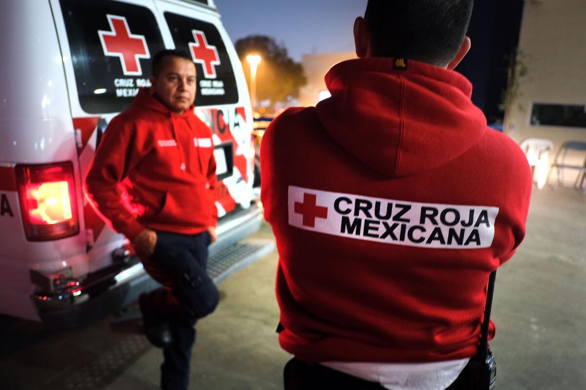 Los paramédicos de la Cruz Roja Mexicana Víctor Ramírez, izquierda, y Sergio García charlan fuera del Hospital General de Tijuana después de dejar a un paciente el viernes.