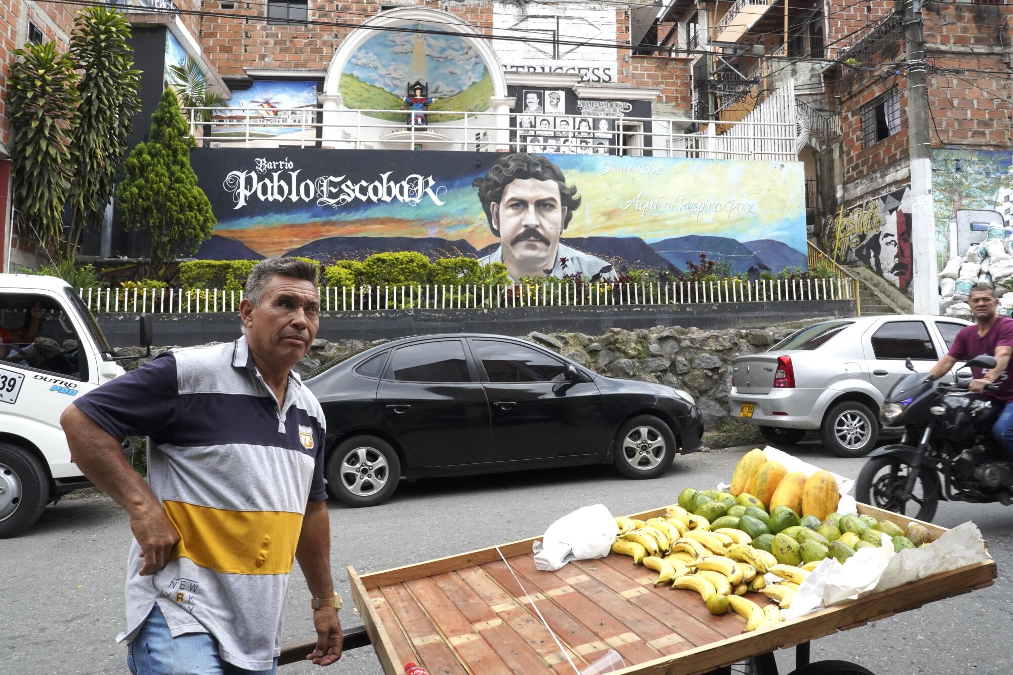 Man sells food in front of a mural.