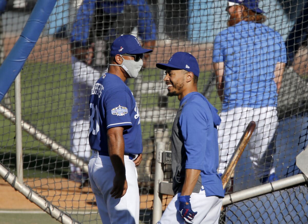 Dodgers right fielder Mookie Betts chats with manager Dave Roberts during practice at Dodger Stadium on Friday.