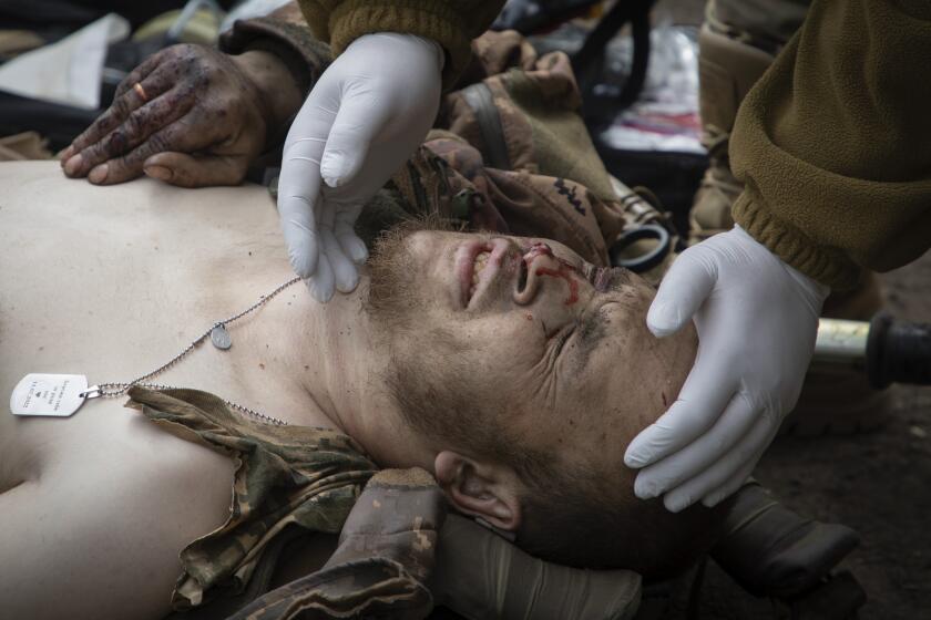 A military medic give first aid to a wounded soldier on the road near Bakhmut, Donetsk region, Ukraine, Thursday, May 11, 2023. (AP Photo/Boghdan Kutiepov)