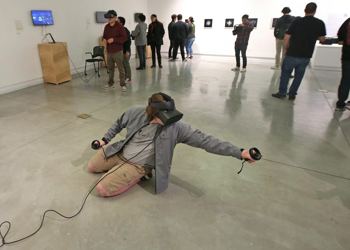 A guest uses a headset to experience a world of a VR Narrative, showing an interpretation of a post-Singularity, at an exhibition of work by students in the new Immersive Media program at OCC, now on display at the Frank M. Doyle Arts Pavilion.