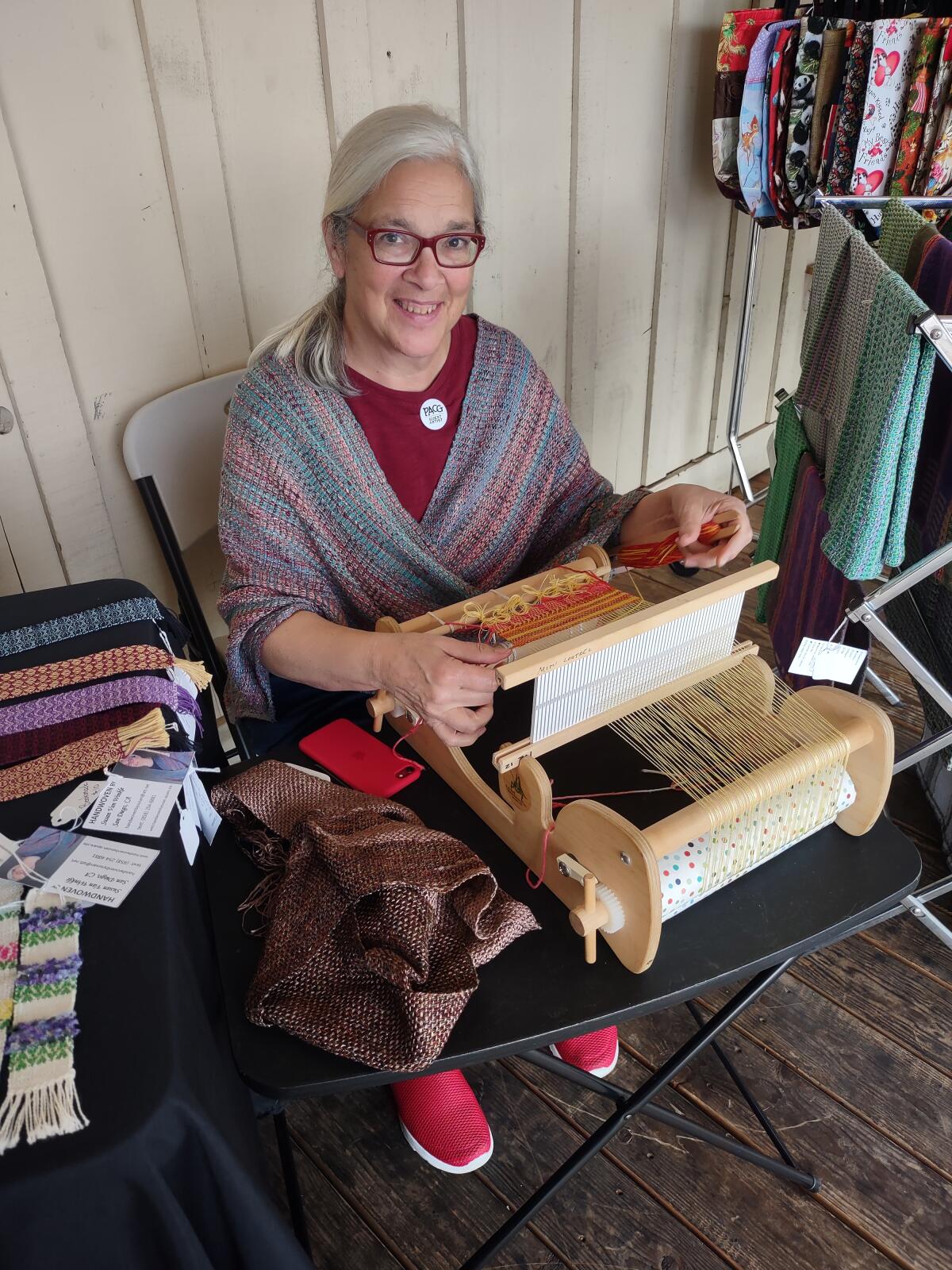 Susan Van Winkle weaves a scarf at her Handwoven By Susan station at the Artisan Market.