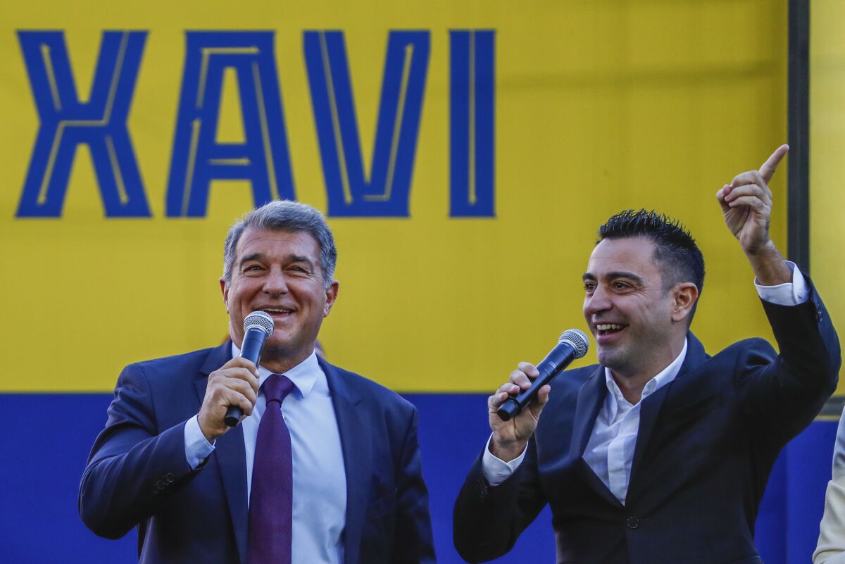 FC Barcelona's new coach Xavi Hernandez, right, gestures next to FC Barcelona president Joan Laporta during his official presentation at the Camp Nou stadium in Barcelona, Spain, Monday, Nov. 8, 2021. Xavi, who thrived in Barcelona's midfield alongside Messi and Andres Iniesta, was officially introduced as coach on the field of the Camp Nou with a reception usually only offered to top players. (AP Photo/Joan Monfort)