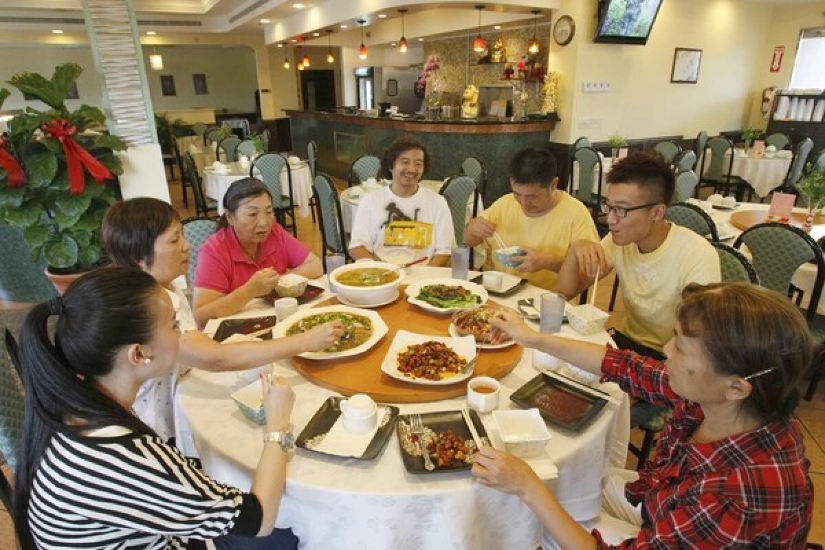 Seated at Taste of Chong Qing Sichuan restaurant in San Gabriel are Sarah Du, left, co-owner Linda Huang, Jing Chen, master chef Qing Jiang, chef Liang Gang, waiter Criss Cai and co-owner Xiao Wen Turner.