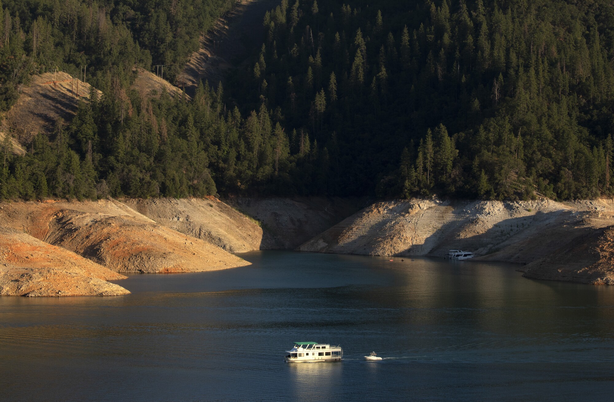 A houseboat is framed by deep bathtub rings from years of drought on California's Shasta Lake.