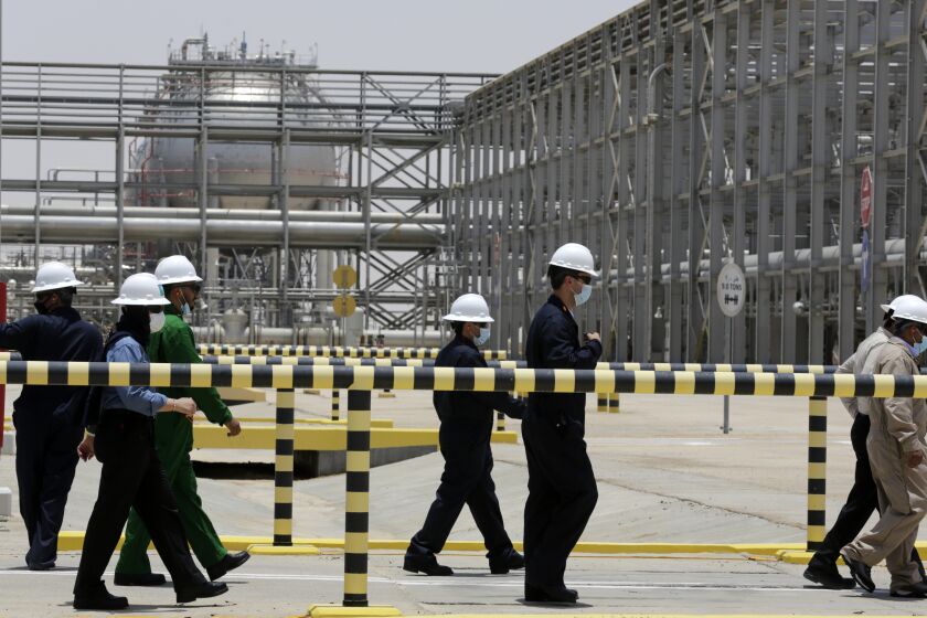 FILE - Saudi Aramco engineers escort reporters on a tour of the Hawiyah Natural Gas Liquids Recovery Plant, which is designed to process 4.0 billion standard cubic feet per day of sweet gas, a natural gas that does not contain significant amounts of hydrogen sulfide, in Hawiyah, in the Eastern Province of Saudi Arabia, on June 28, 2021. Saudi Arabia's state-owned oil giant Aramco will invest billions of dollars in China's downstream petrochemicals industry, including the construction of a new refinery, the company said in deals announced Sunday and Monday.(AP Photo/Amr Nabil, File)