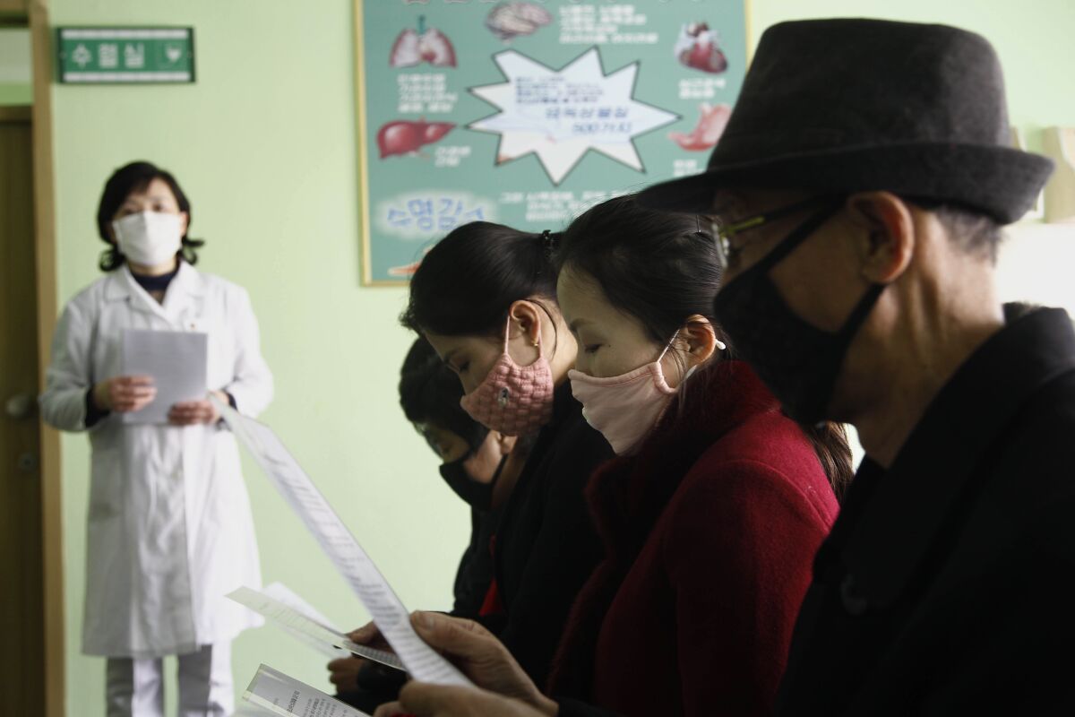 People review information explaining the coronavirus at the Pyongchon District People's Hospital in Pyongyang, North Korea.