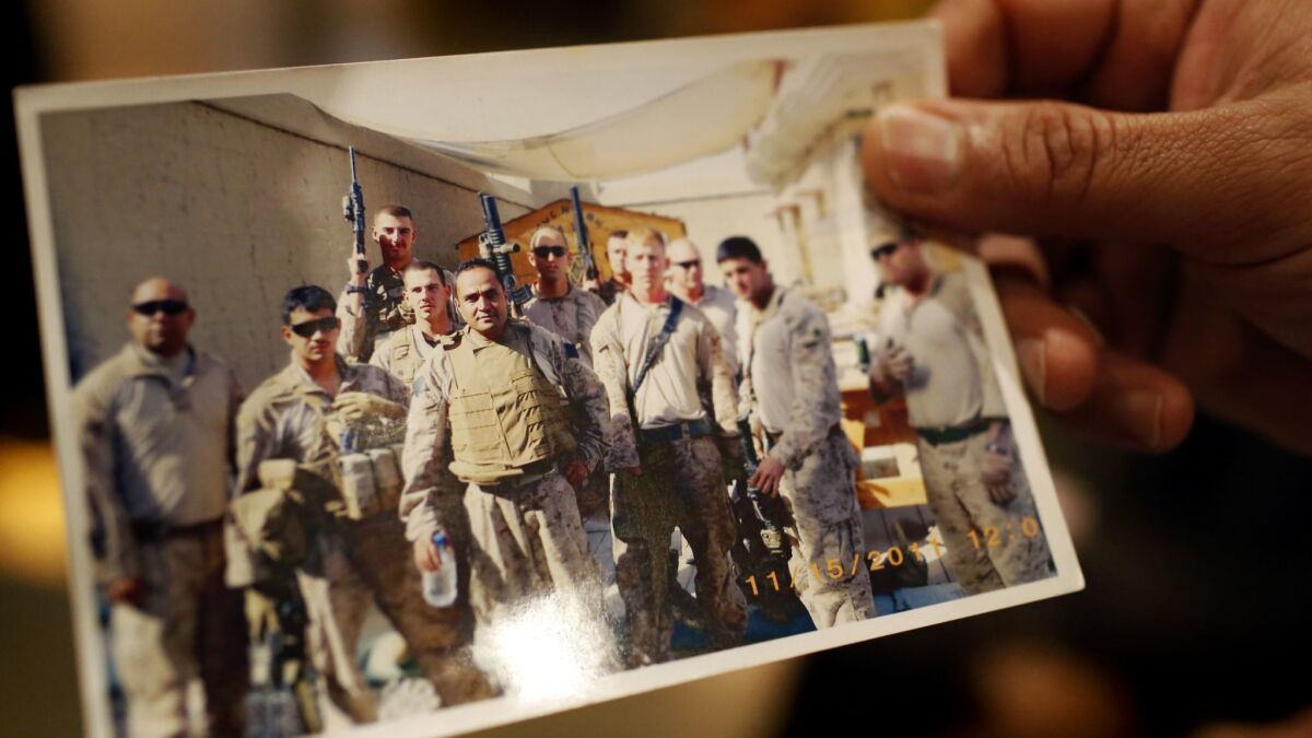 Bashir Kashefi holds a photo of himself, center, when he worked as an interpreter for the U.S. military in Afghanistan.