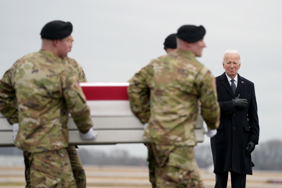 President Biden stands by as Army soldiers in fatigues carry a flag-draped coffin.