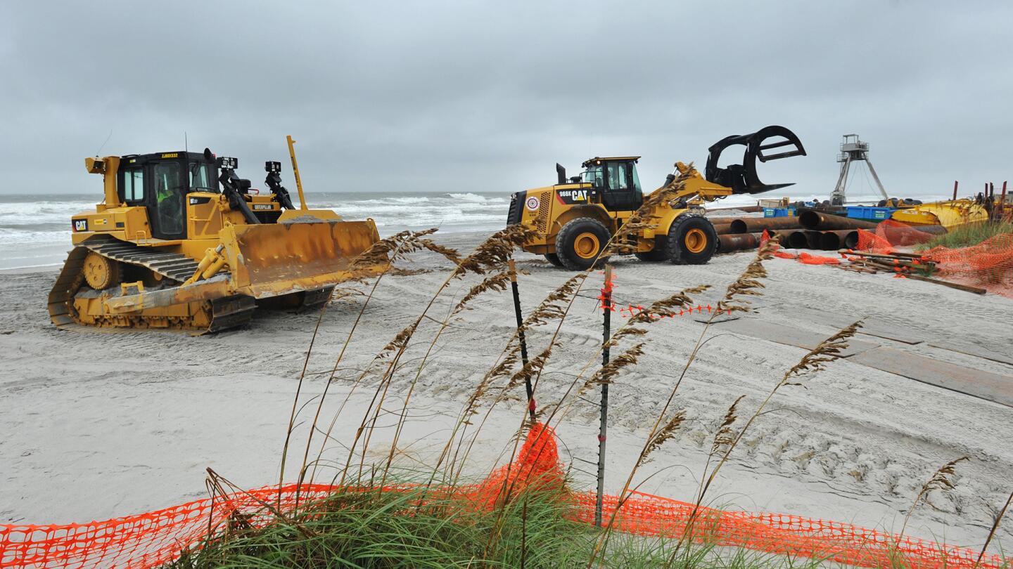 Workers remove pipes and other equipment related to a beach dredging project in preparation for Hurricane Matthew Wednesday, Oct. 5, in Jacksonville Beach, Fla.