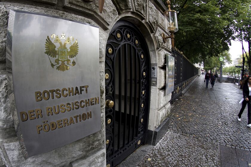 FILE - People walk past an entrance of the Russian embassy in Berlin, Germany, Friday, Sept. 4, 2020. Germany says it has told Russia to close four out of five consulates in Germany in a tit-for-tat move after Moscow set a limit for the number of German embassy staff and related bodies that can operate in Russia. (AP Photo/Michael Sohn, File)