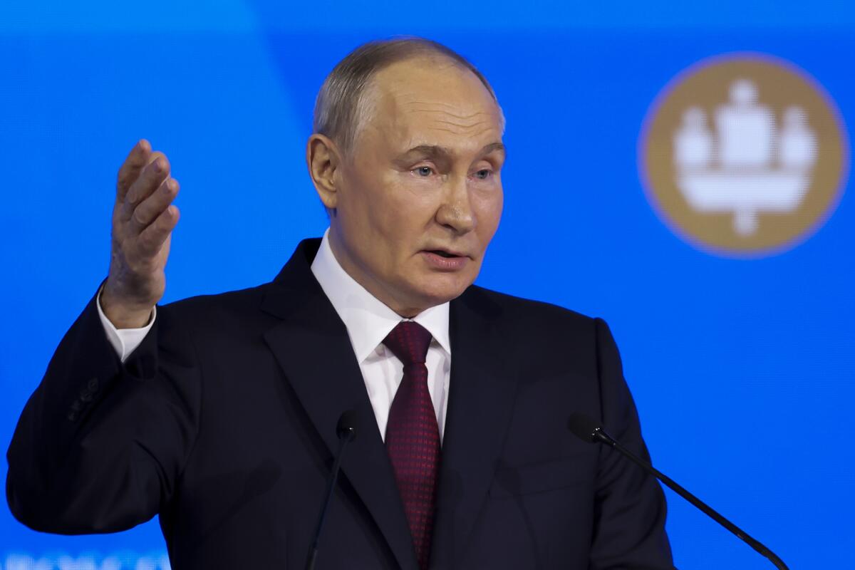 Russian President Vladimir Putin gestures as he speaks into a microphone.