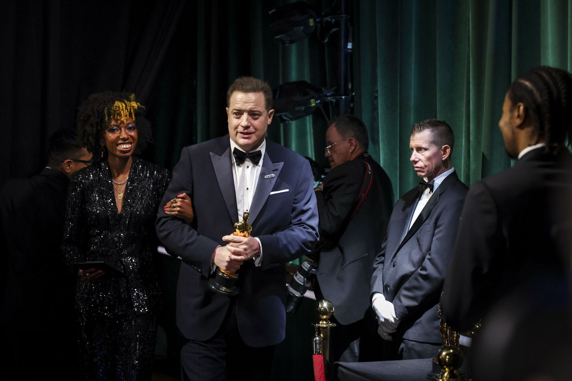 A man in a tuxedo holding an Oscar backstage at the 95th Academy Awards.